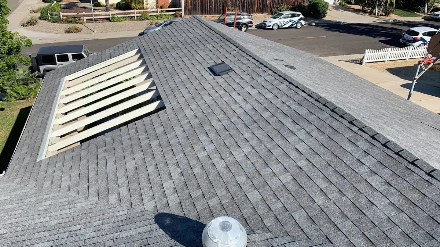 Exposed wood roof decking during a San Diego tear-off, where hidden rot beneath the old roof drives up the final cost.