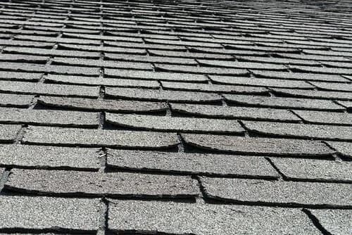 An aging San Diego asphalt shingle roof with shingles curling and lifting from age.