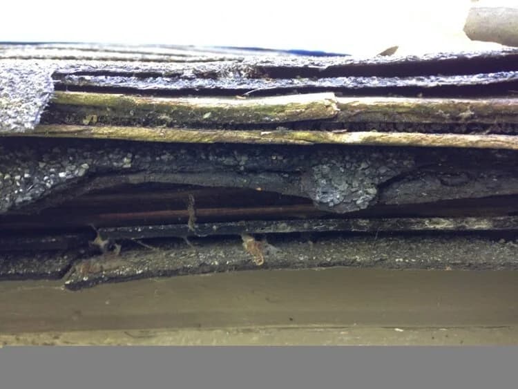 A severely deteriorated, rotted roof edge in San Diego with decayed, layered shingles after years of neglect.