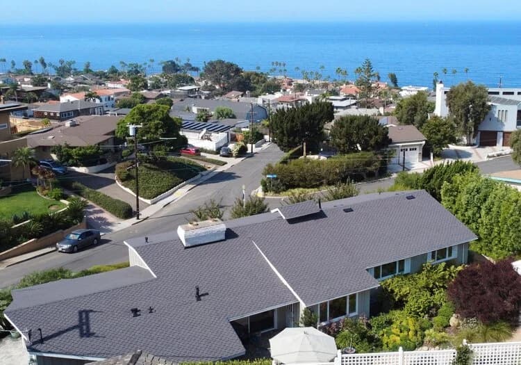 Aerial view of a single-story San Diego home with a gray shingle roof in a coastal neighborhood.
