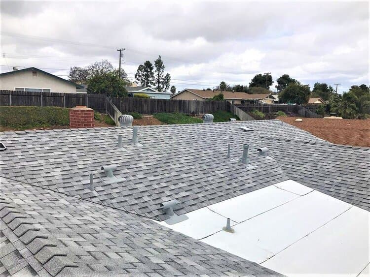 Photo of a recently finished shingle roof, with the proper precautions against wind damage.
